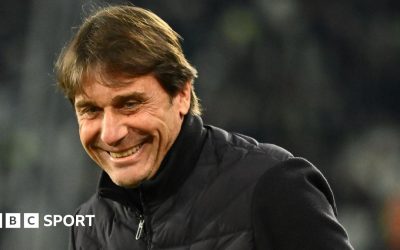 Head and shoulders view of a smiling Antonio Conte in a black, zipped-up jacket