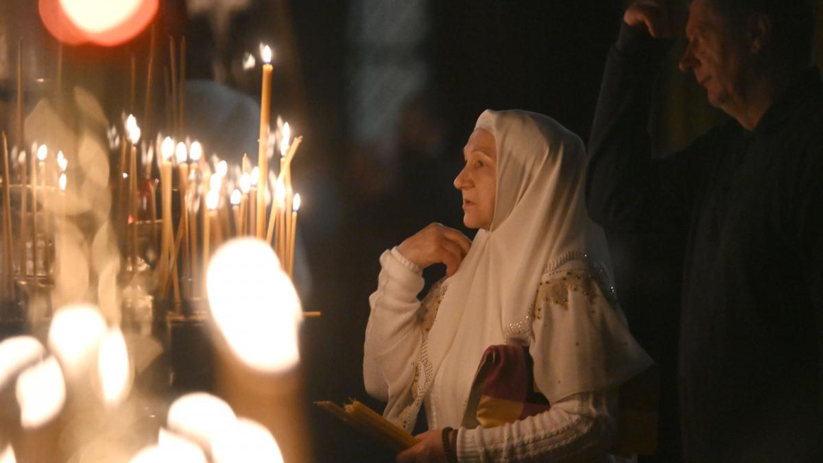 femeie care se roaga in biserica in apropierea unor lumanari