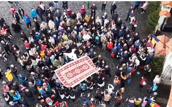Junii Brașoveni sfidează gerul în Piața Unirii: Aruncatul în țol, spectacol tradițional